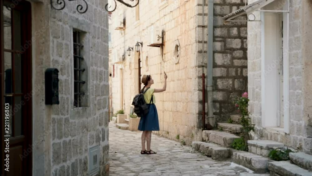 Young cheerful traveler girl, walking in european city. Travel at Montenegro and looking Perast landmarks. Pretty female photographer with map at the city center make a photo. Young cheerful traveler girl, walking in european city. Travel at Montenegro and looking Perast landmarks. Pretty female photographer with map at the city center make a photo.