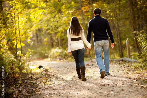 Couple Holding Hands Walking in Autumn Woods