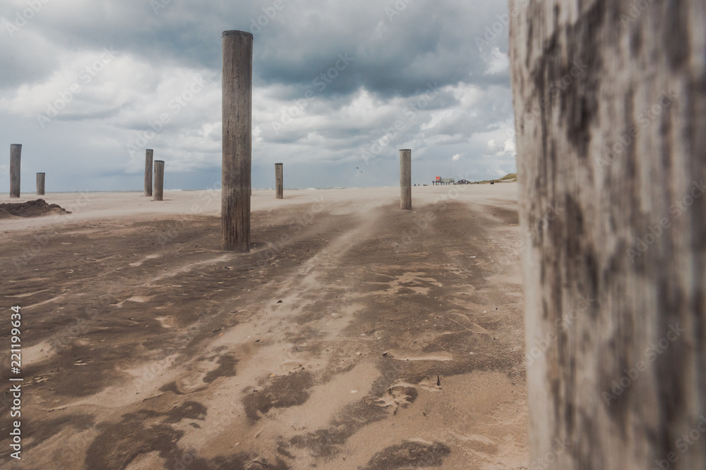 Long shutter photo of wooden on sandy beach with white clouds and waves of the North Sea Long shutter photo of wooden on sandy beach with white clouds and waves of the North Sea