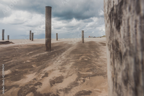 Long shutter photo of wooden on sandy beach with white clouds and waves of the North Sea