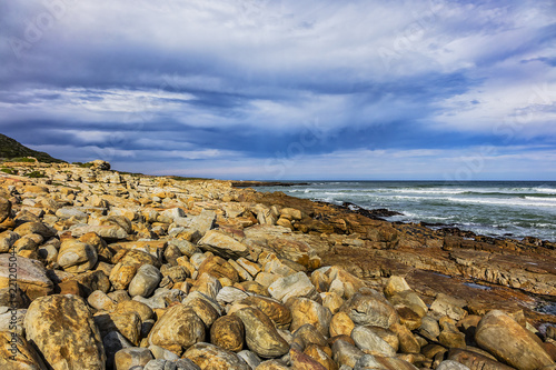 Picturesque view of the rocky shoreline of Atlantic Ocean and Platboom Beach. Platboom Bay is a beautiful beach along coastline nestled in Cape of Good Hope Nature reserve, Cape Town, South Africa.