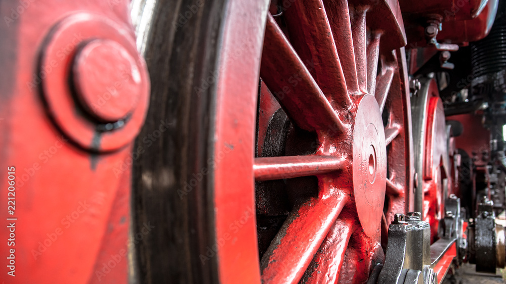 Red spoke wheels with rods and pistons of old train locomotive at ubex location with authentic industrial details and craftsmanship along the rail way and station Red spoke wheels with rods and pistons of old train locomotive at ubex location with authentic industrial details and craftsmanship along the rail way and station