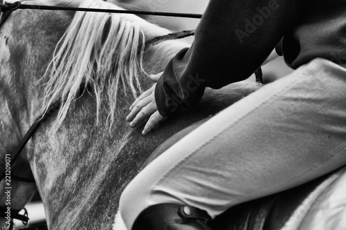 Young woman riding horse with hand showing gentle touch to animal, in black and white.