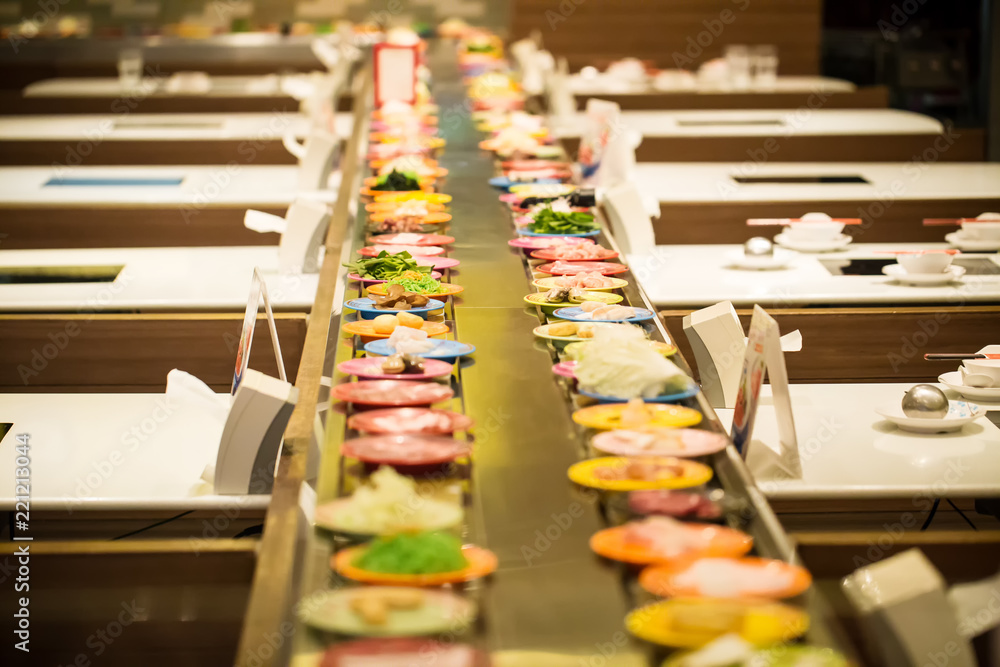 Obraz premium Row of dishes in belt japanese food buffet. trendy popular restaurants. healthy food type of boiled instead fried trans-fat. image for background, objects and copy space.