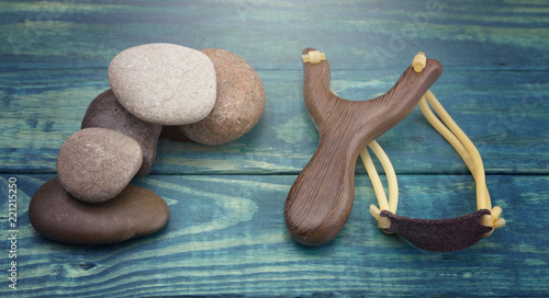 Slingshot and Five Smooth Stones on a Blue Table