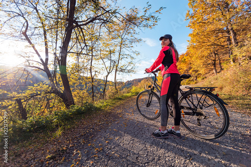Active woman riding bicycle at autumn day