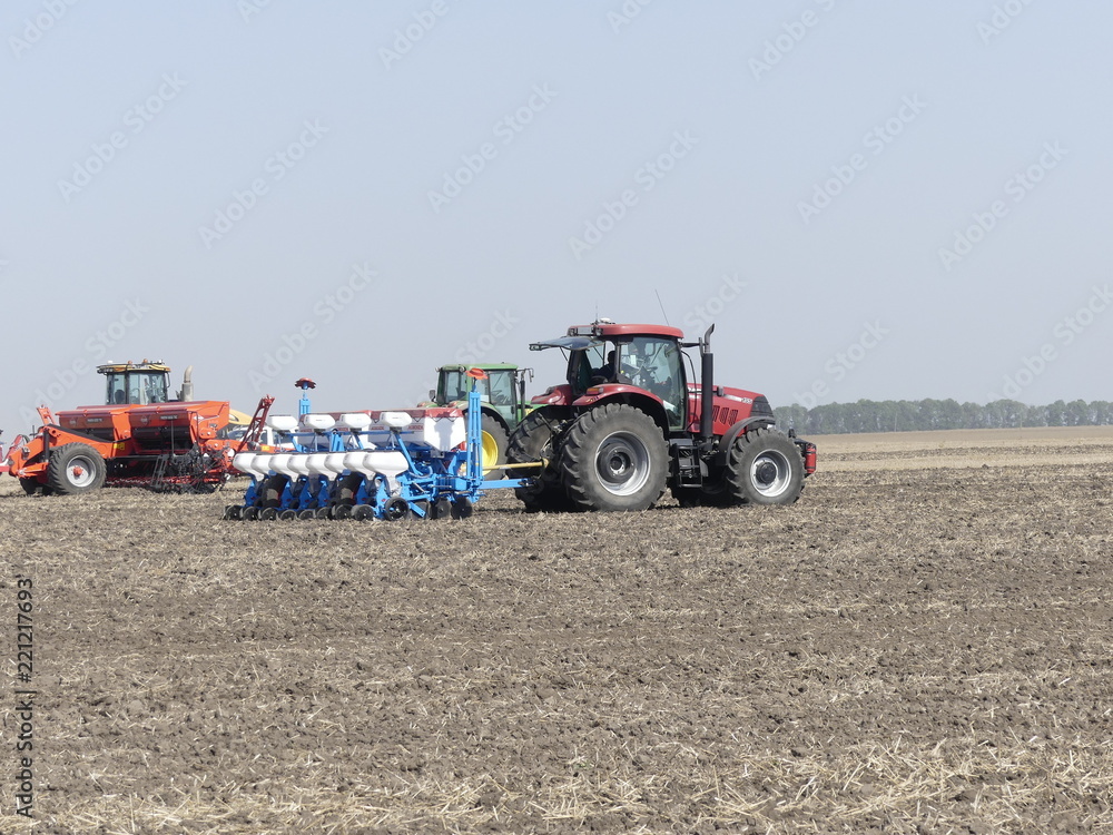 Obraz premium Exhibition of agricultural machinery. Agrotechnics works in the field. Tractor sows in the field