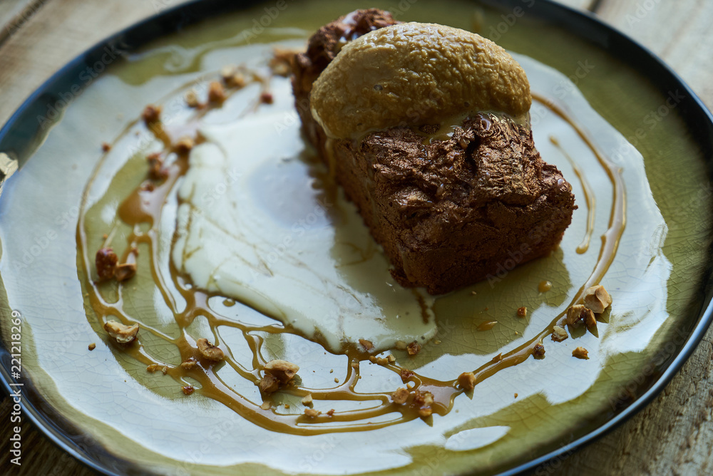 Classic French dessert. Chocolate fondant lava cake with custard and pistachio ice cream, cocoa powder, mint leaves on wooden table background , close up. Classic French dessert. Chocolate fondant lava cake with custard and pistachio ice cream, cocoa powder, mint leaves on wooden table background , close up.
