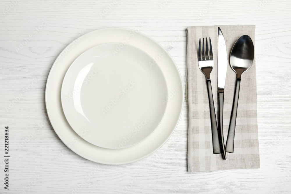 Plates and cutlery on wooden table, top view. New setting Plates and cutlery on wooden table, top view. New setting