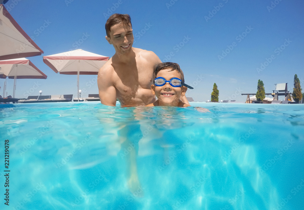 Father and son in swimming pool on sunny day
