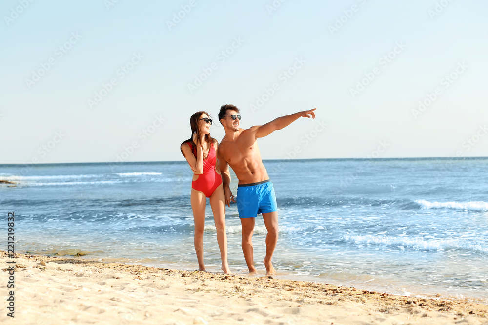 Happy young couple walking together on beach