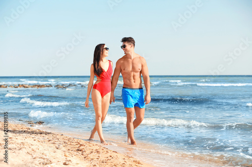 Happy young couple walking together on beach