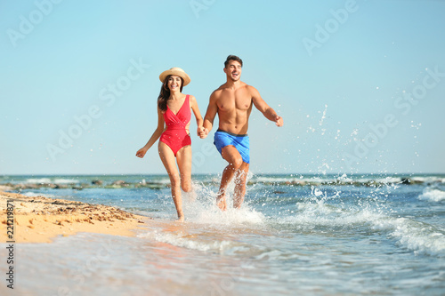 Happy young couple having fun at beach on sunny day