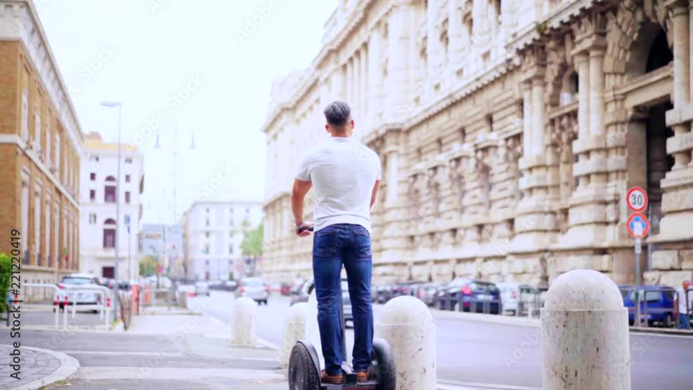 Man riding a gyroscooter, Tourist travel in the street in the city near the beautiful old buildings. Slow motion 100fps Man riding a gyroscooter, Tourist travel in the street in the city near the beautiful old buildings. Slow motion 100fps