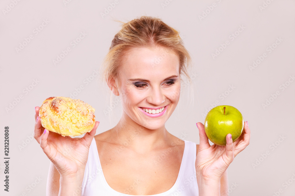 Woman holds cake and fruit in hand choosing Woman holds cake and fruit in hand choosing