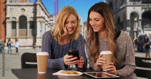 Cute young Caucasian women looking at smartphone by Saint Mark's Basilica
