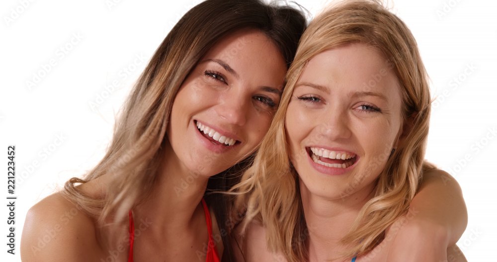 Portrait of two young white females posing happily together on white copy space Portrait of two young white females posing happily together on white copy space