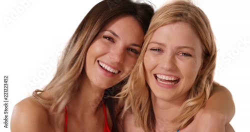 Portrait of two young white females posing happily together on white copy space