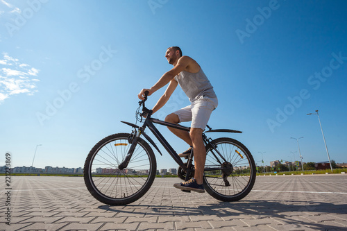 Fototapeta Naklejka Na Ścianę i Meble -  beautiful young guy with a bicycle against the sky on a sunny day