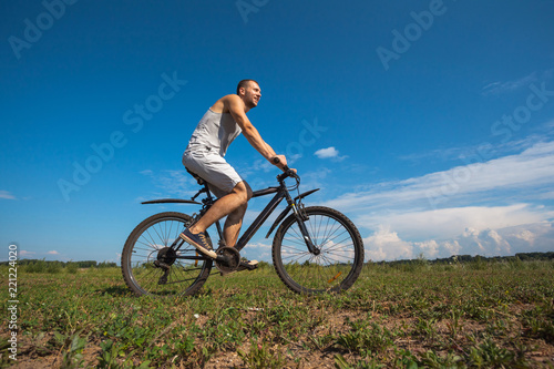 Fototapeta Naklejka Na Ścianę i Meble -  beautiful young guy with a bicycle against the sky on a sunny day