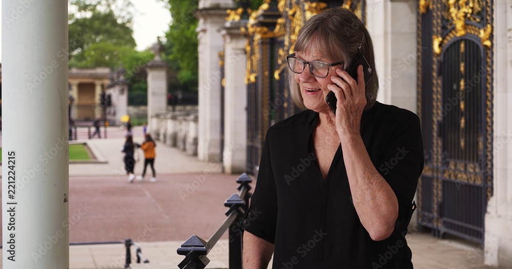 Fototapeta premium Older woman chatting on a cellphone with someone while on vacation in London