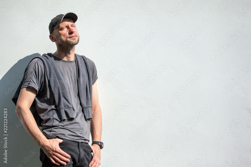 brutal man with a bristle enjoys the sun against a white wall background brutal man with a bristle enjoys the sun against a white wall background