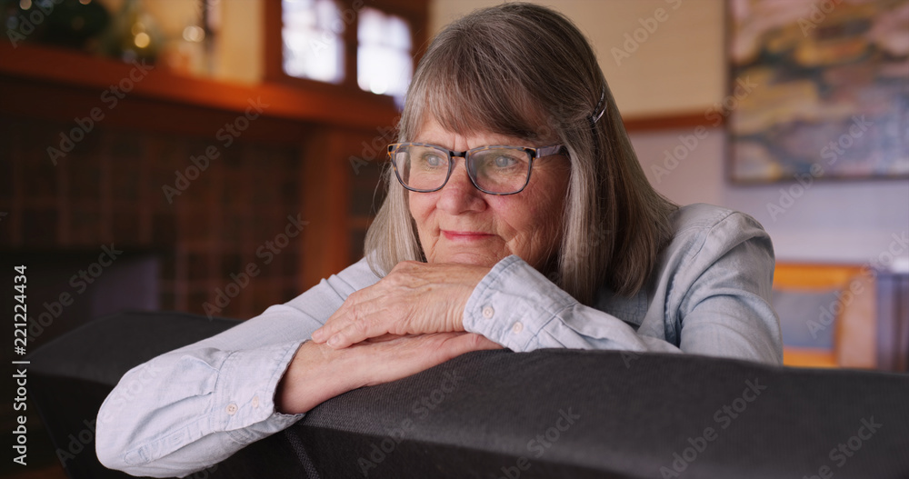Close-up of content mature woman relaxed on sofa daydreaming inside home Close-up of content mature woman relaxed on sofa daydreaming inside home