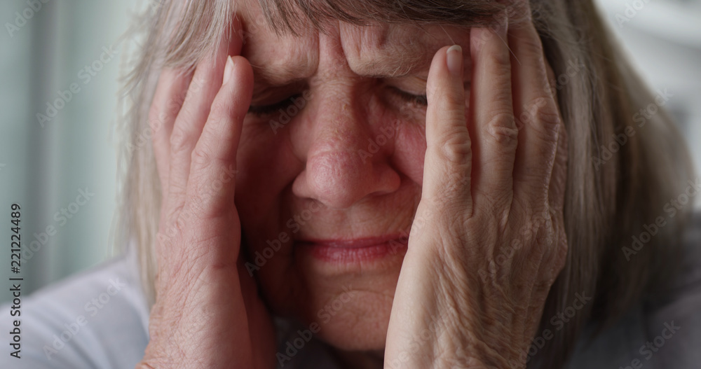 Close-up of stressed senior woman face in pain indoors inside her home Close-up of stressed senior woman face in pain indoors inside her home