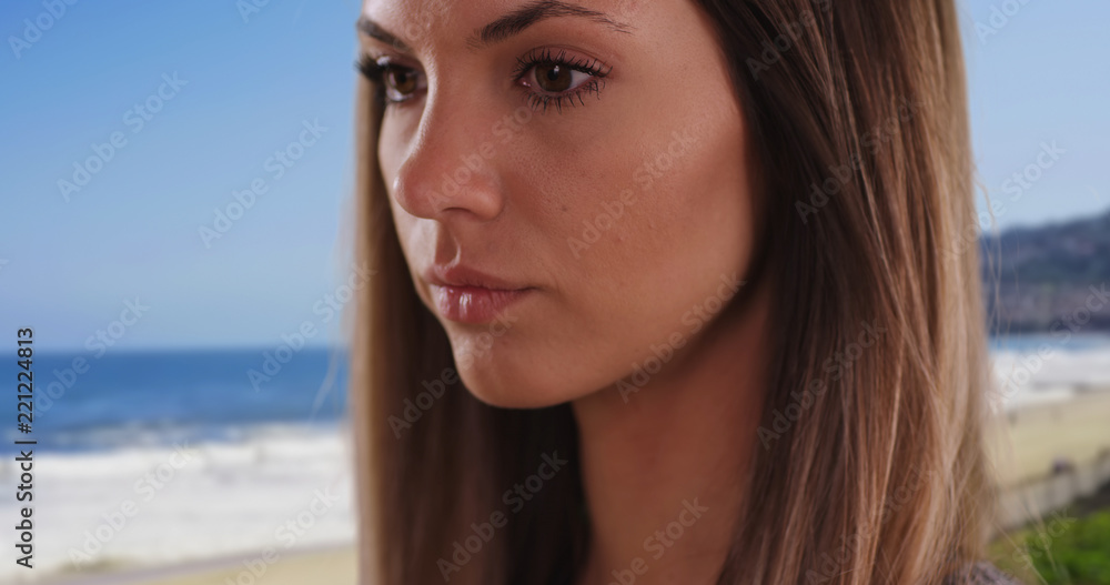 Close-up portrait of pretty brunette deep in thought in serene beach setting Close-up portrait of pretty brunette deep in thought in serene beach setting