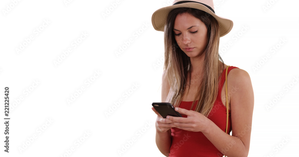 Caucasian hipster girl in her 20s texting on smartphone on solid white backdrop