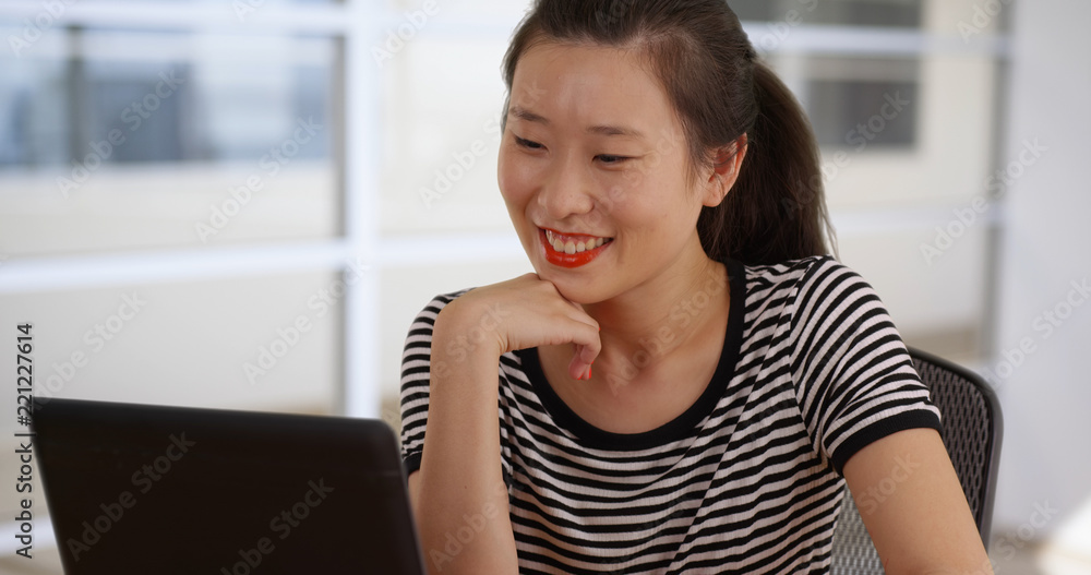 Smiling young woman in her 20s reading with portable laptop computer Smiling young woman in her 20s reading with portable laptop computer