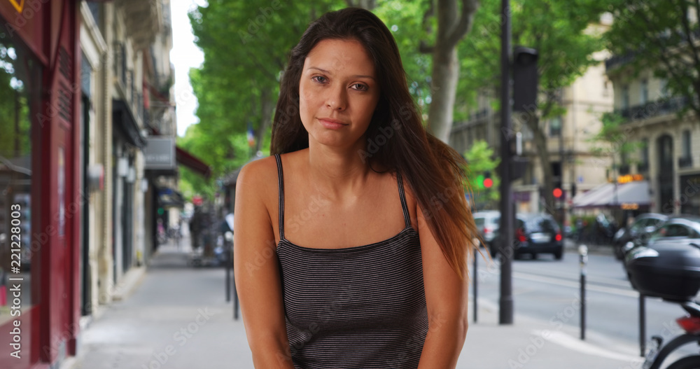 Pretty Caucasian girl wearing striped tank top standing on street in Paris