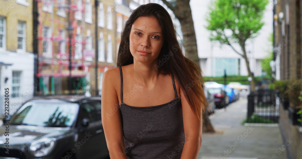 Pretty Caucasian girl wearing tank top standing on London street with apartments
