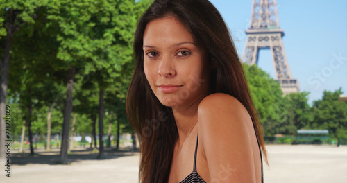 Close-up of millennial tourist wearing tank top standing near the Eiffel Tower
