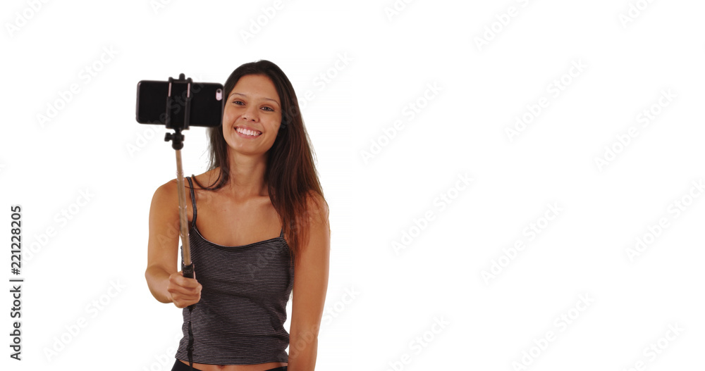 Pretty tourist woman with selfie stick posing for pictures on white background