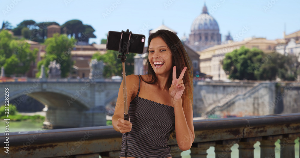 Young tourist woman on bridge in Rome taking selfies near St. Peters Basilica