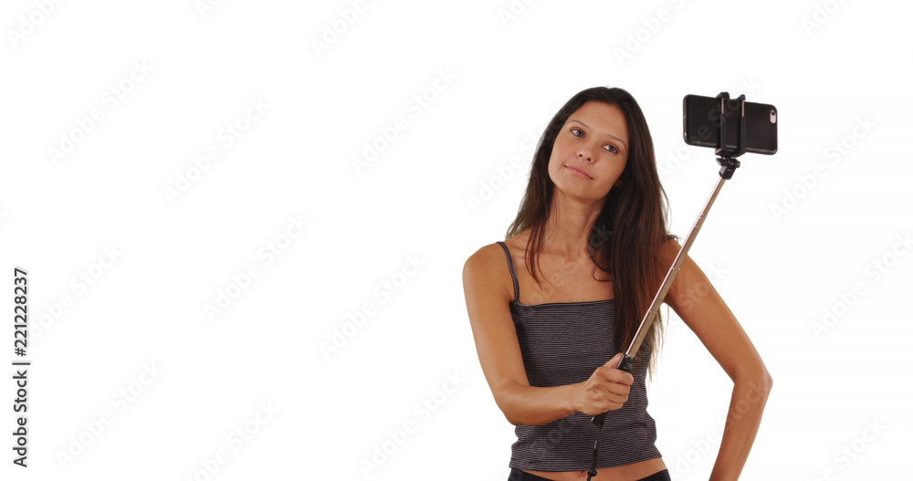 Cute brunette traveler girl using selfie stick in studio with copy space Cute brunette traveler girl using selfie stick in studio with copy space