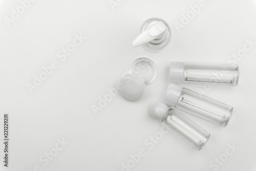 top view of the empty clear plastic portable cream jar and liquid containers on white background