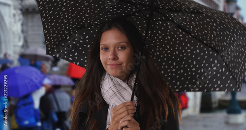 Happy millennial female on Venice city street with polka dot umbrella