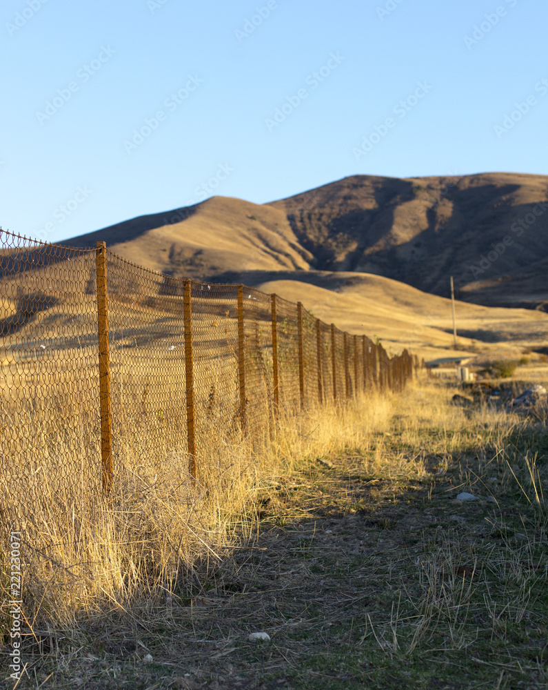 metal fence in the field at sunset metal fence in the field at sunset