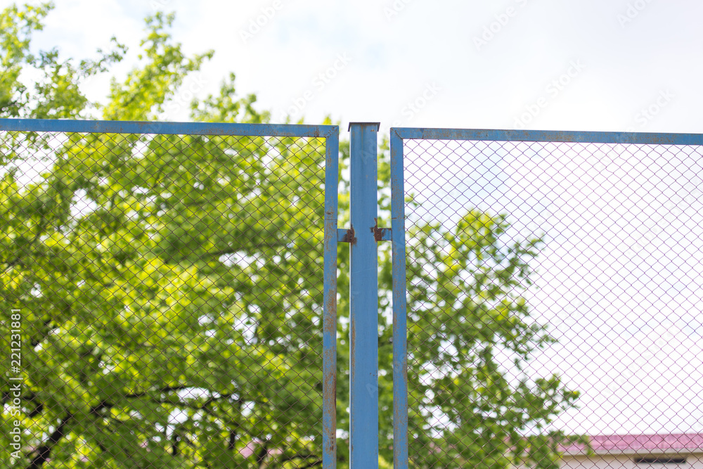 Green wire fence on background of green trees Green wire fence on background of green trees