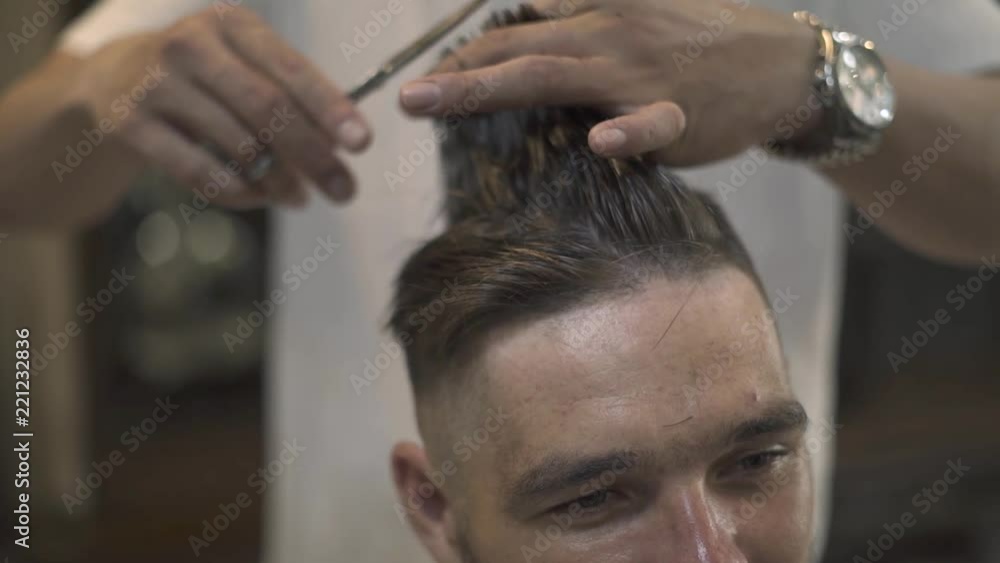 Face young man getting stylish hairdo in barbershop. Haircutter combing hair and cutting hair with hairdressing scissors in male salon. Close up hand hairdresser cutting wet male hair. Face young man getting stylish hairdo in barbershop. Haircutter combing hair and cutting hair with hairdressing scissors in male salon. Close up hand hairdresser cutting wet male hair.