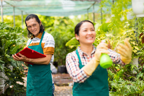 Cheerful Asian gardeners enjoying working in orangery