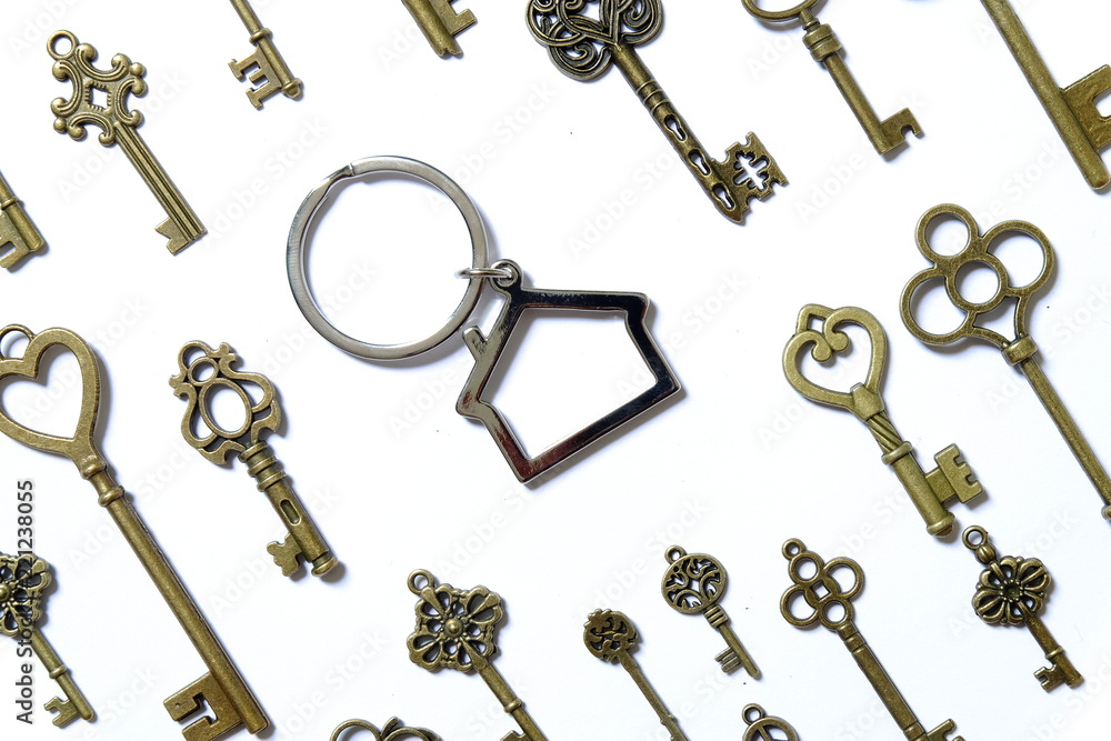 Real estate or property theme. House shape key chain with variety of keys on white background Real estate or property theme. House shape key chain with variety of keys on white background