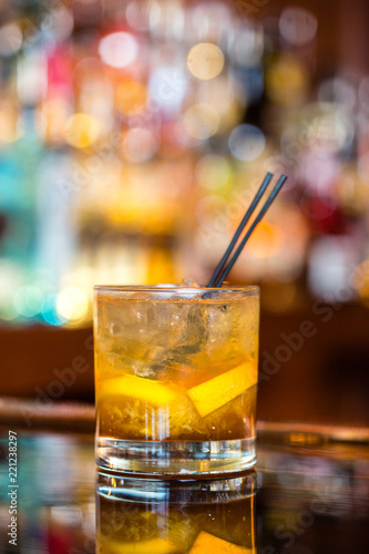 A cocktail on the rocks with orange slices and straws photo