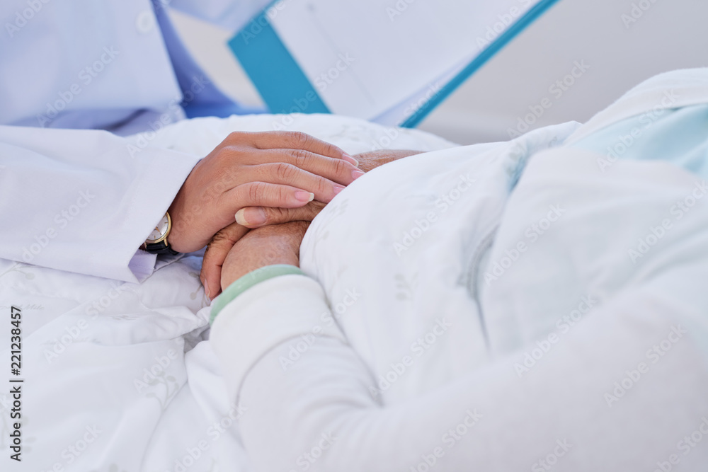 Hand of doctor touching aged patient to support and reassure her Hand of doctor touching aged patient to support and reassure her