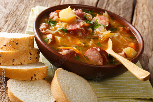 Homemade spicy soup of sauerkraut with sausages and vegetables close-up in a bowl. horizontal photo