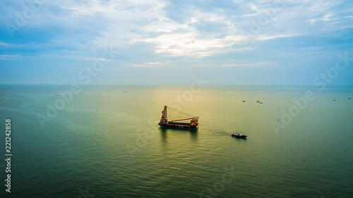 Fototapeta Naklejka Na Ścianę i Meble -  Small towing tugboat dragging the huge Dredger ship in the sea. Drilling industry in the ocean. image for background, wallpaper, advertisement,objects and copy space.