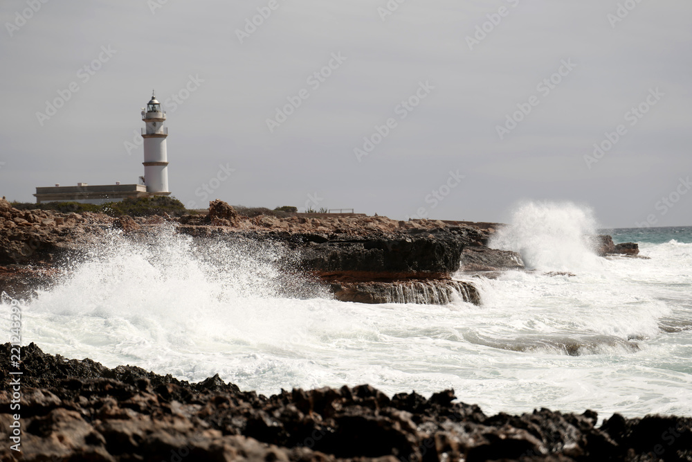 Waves crashing over rocks at lighthouse