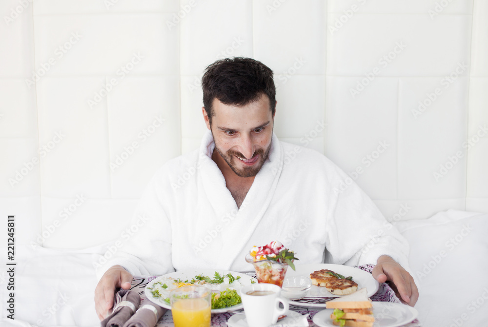 Happy single man eating breakfast in bed Happy single man eating breakfast in bed